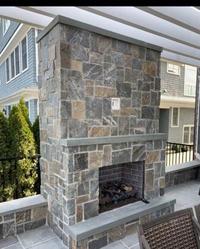 Outdoor fireplace with masonry accented chimney stack installed and maintenanced by Alpine Fireplaces.