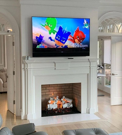 Active fireplace burning under wall mounted TV from Alpine Fireplaces. Find out how.